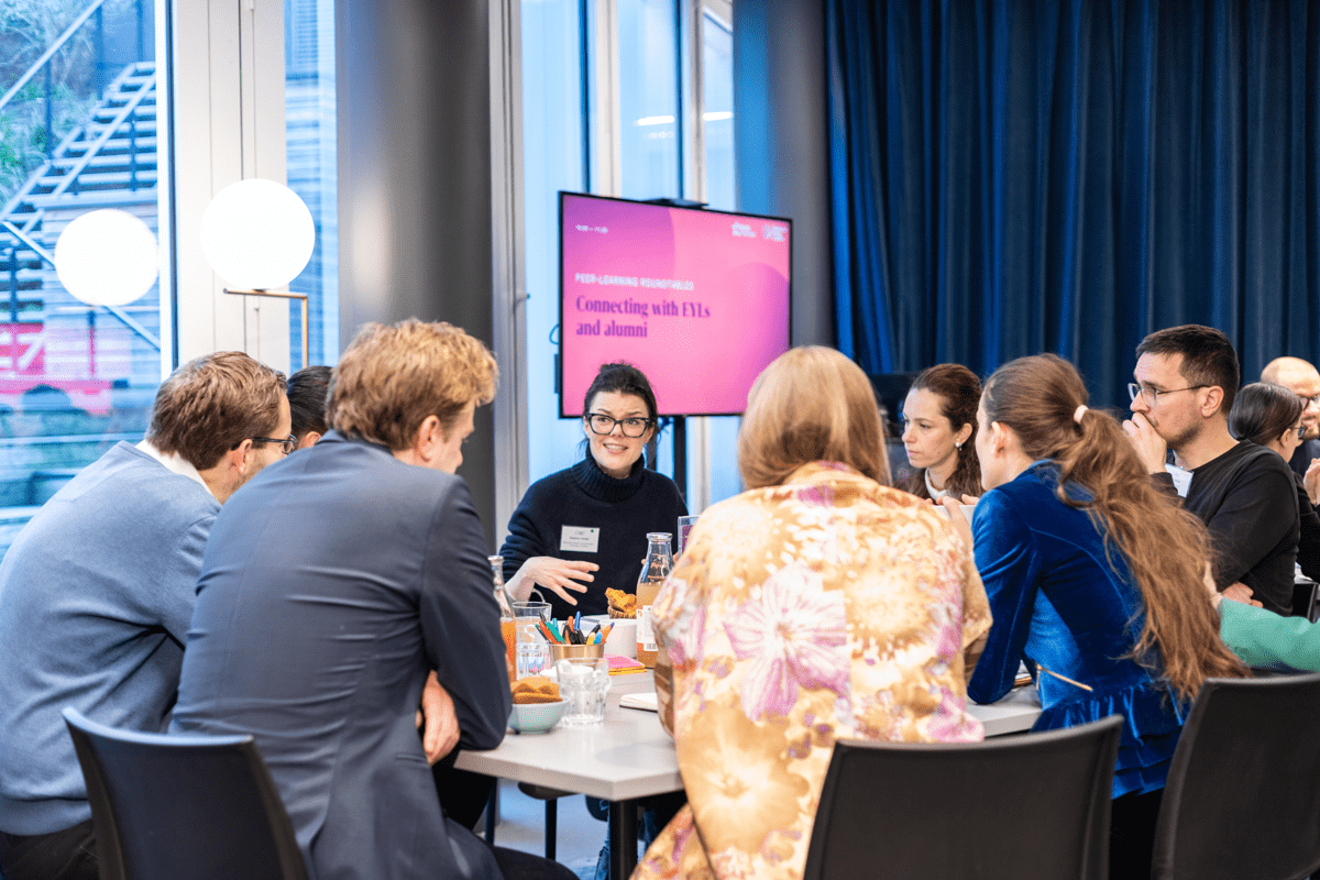 A group of participants sit around a table and discuss together
